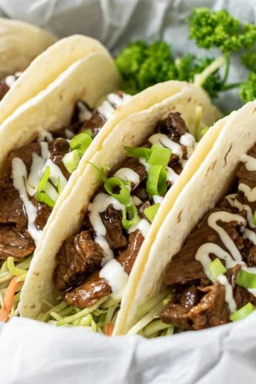four Korean BBQ Tacos in a paper lined basket with parsley