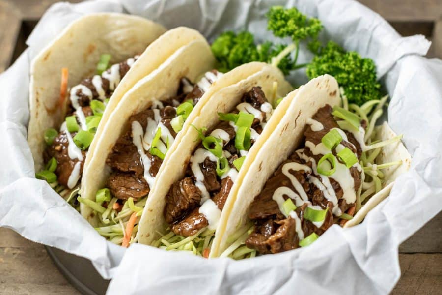 four Korean BBQ Tacos in a paper lined basket with parsley