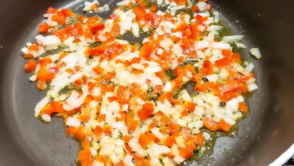 onion and red pepper cooking in a pan.