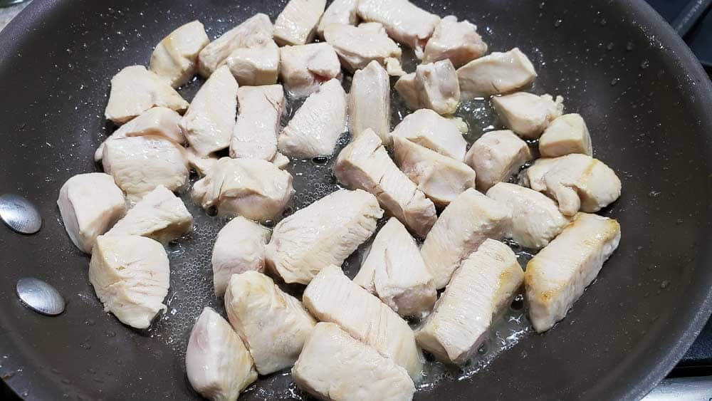 cubed chicken cooking in a pan