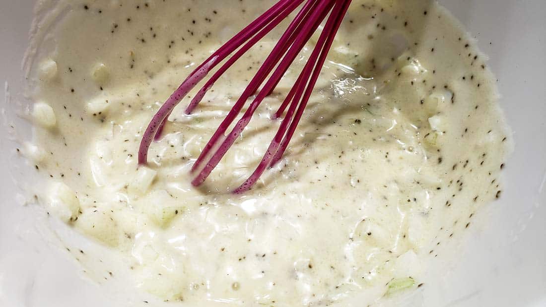 coleslaw dressing mixed in a bowl with a whisk.