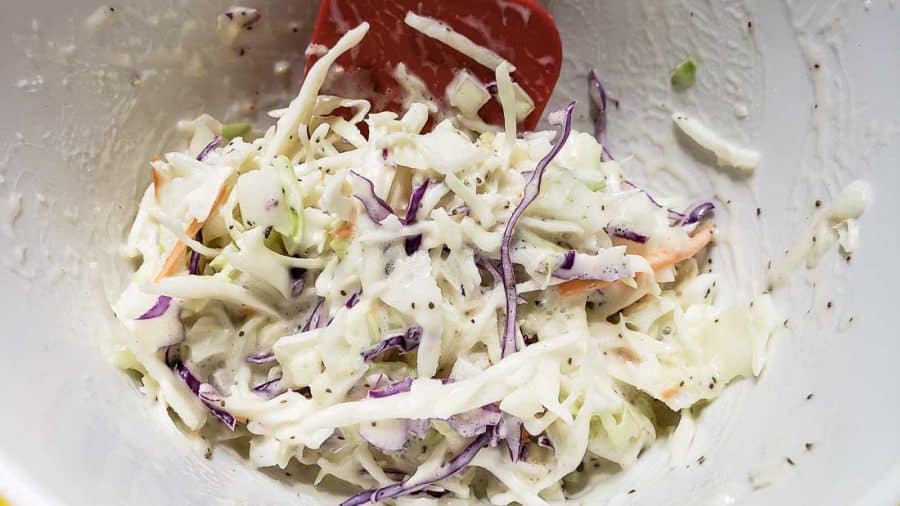 coleslaw dressing mixed into shredded cabbage slaw mix in a bowl