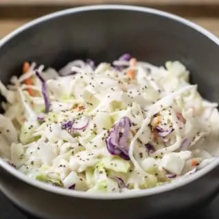 classic creamy coleslaw in a bowl with a fork on the side