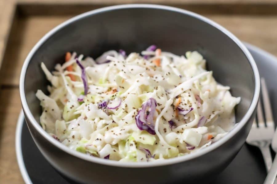classic creamy coleslaw in a bowl with a fork on the side