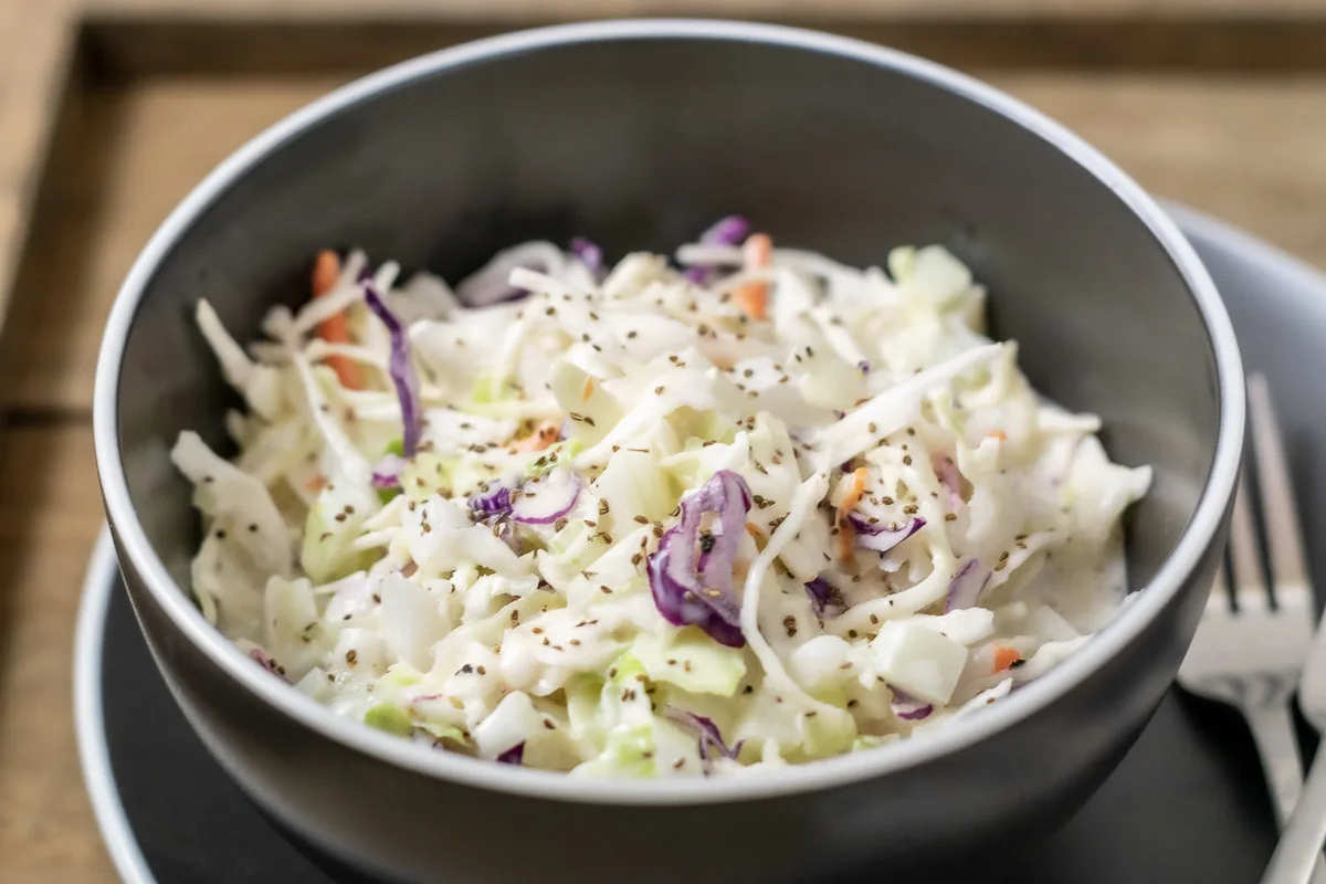 classic creamy coleslaw in a bowl with a fork on the side.