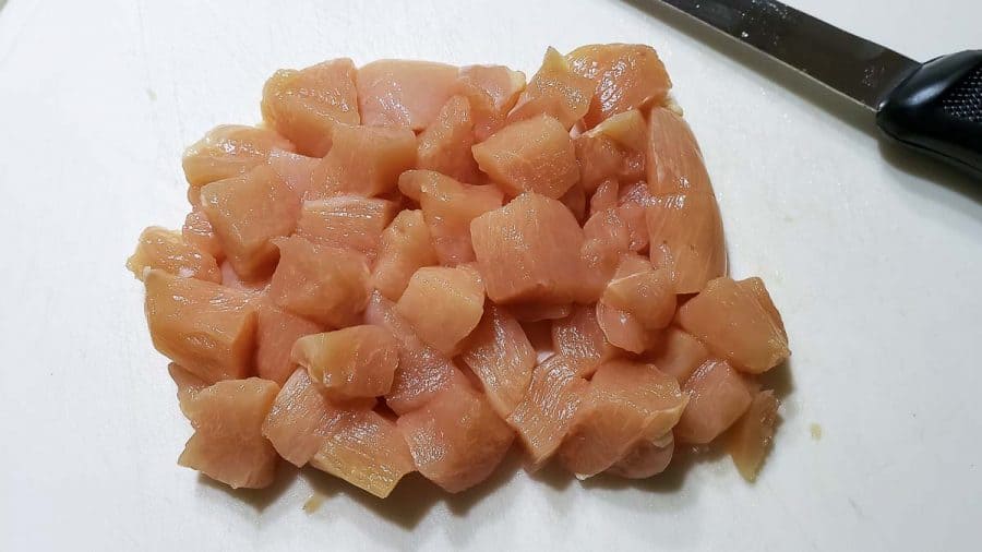 diced chicken on a cutting board with a knife
