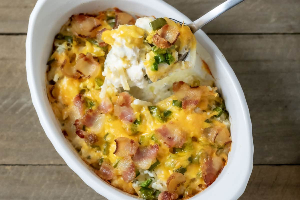 Jalapeño Popper Casserole loaded with chicken with a spoon lifting up some of the casserole out of the dish.