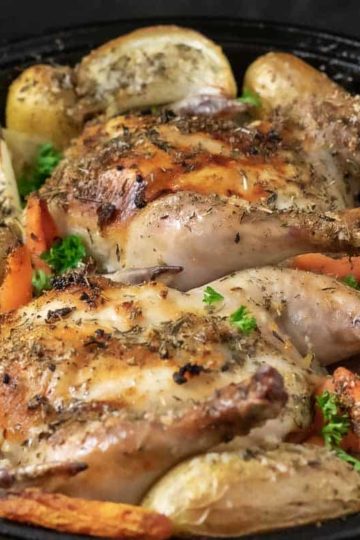a cast iron skillet filled with Oven Roasted Cornish Hens and Veggies