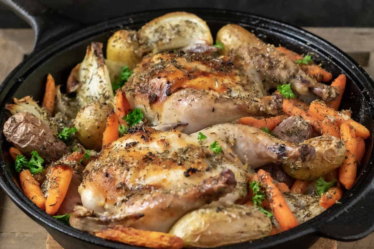 a cast iron skillet filled with Roasted Cornish Hen with Potatoes and Carrots.
