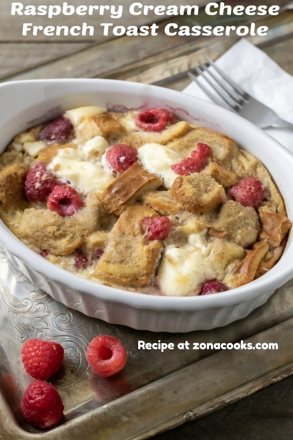 a graphic of Raspberry Cream Cheese French Toast Casserole on a tray with a napkin and fork