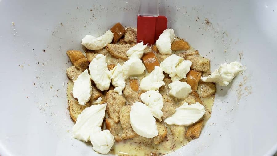 spoonful's of cream cheese mixture dropped into bowl with bread mixture.