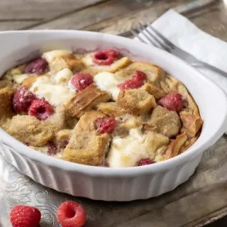 Raspberry Cream Cheese French Toast Casserole in a dish on a tray with a fork and napkin.