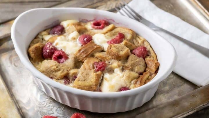 Raspberry Cream Cheese French Toast Casserole in a dish on a tray with a fork and napkin