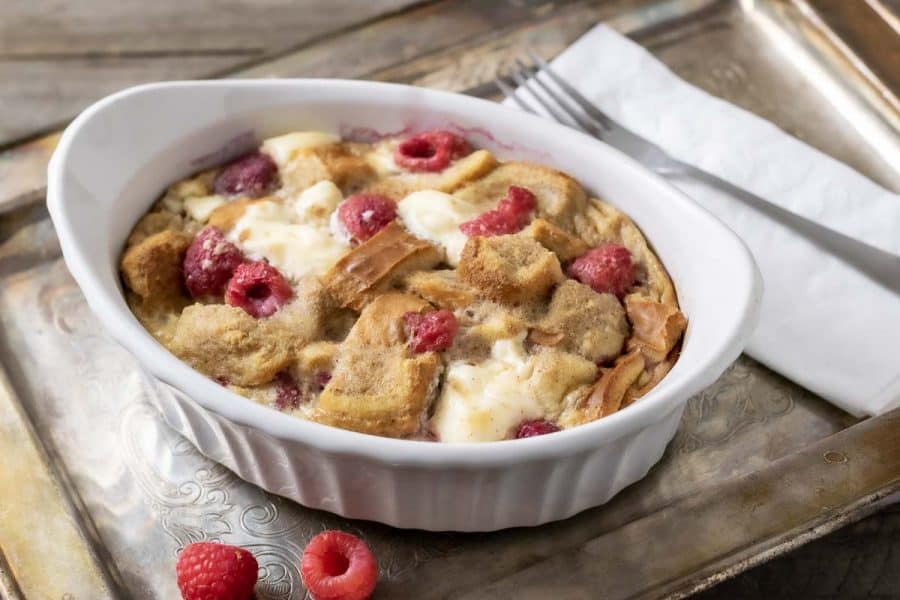 Raspberry Cream Cheese French Toast Casserole in a dish on a tray with a fork and napkin.