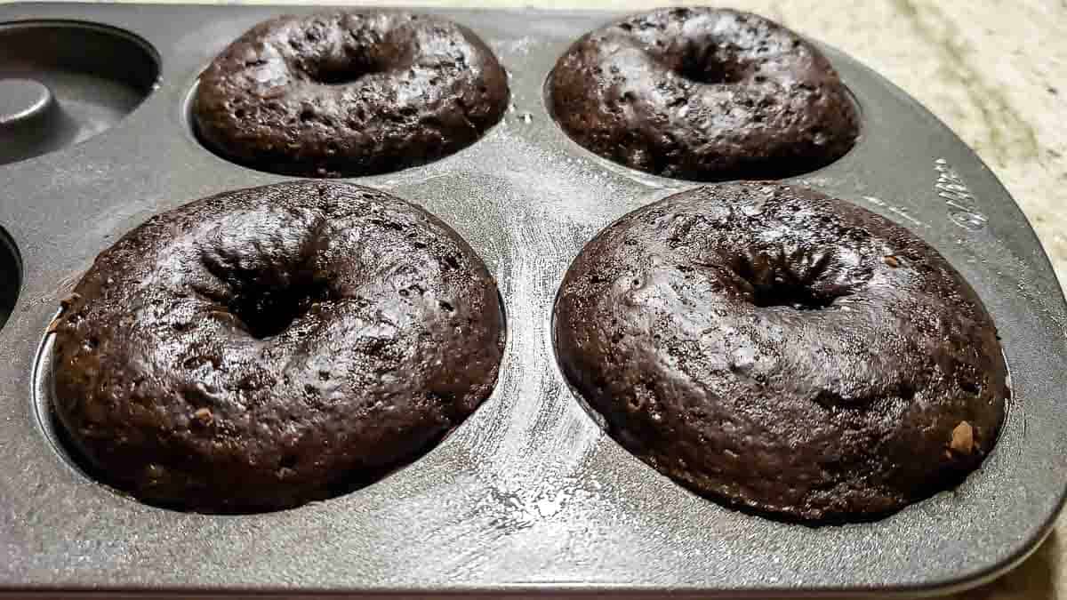 4 baked chocolate donuts in a donut pan