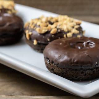4 Baked Chocolate Donuts with Chocolate Glaze on a plate and two have nuts on top