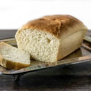 a loaf of white bread on a tray with one slice laying down