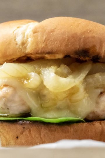 a close up front view of a french onion chicken sandwich on a crumpled paper