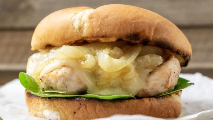 a close up front view of a french onion chicken sandwich on a crumpled paper
