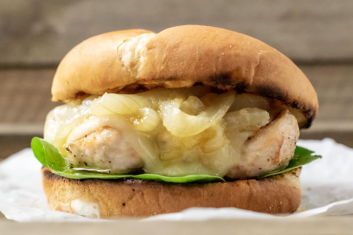 a close up front view of a french onion chicken sandwich on a crumpled paper
