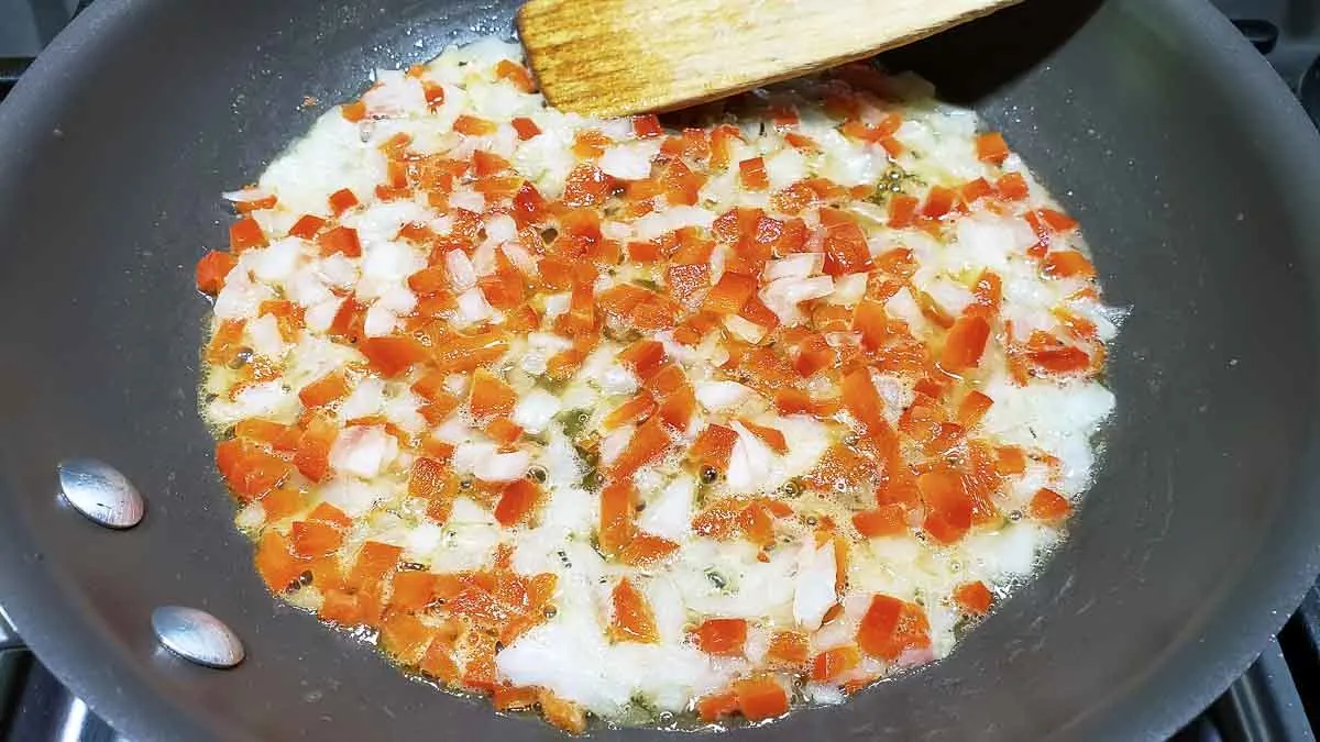 diced onion and red pepper cooking in a pan.