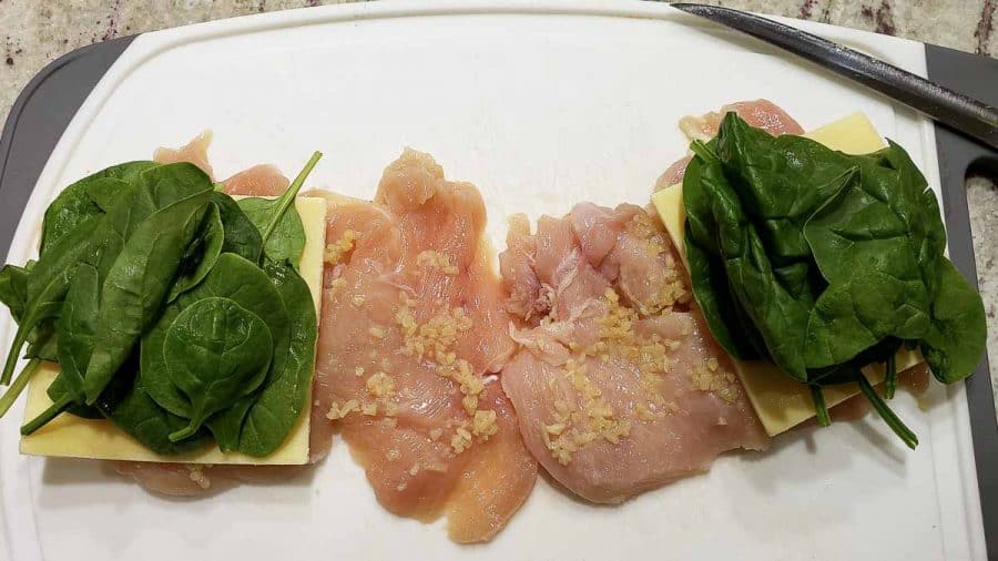 spinach leaves layered over cheese, garlic, and chicken