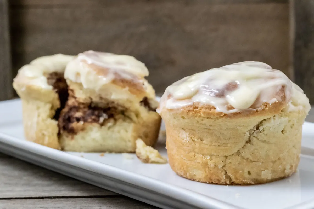 two jumbo cinnamon rolls on a platter with one giant roll spit open.
