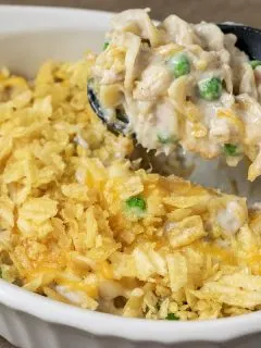 tuna noodle casserole in a baking dish with a spoon lifting out some casserole