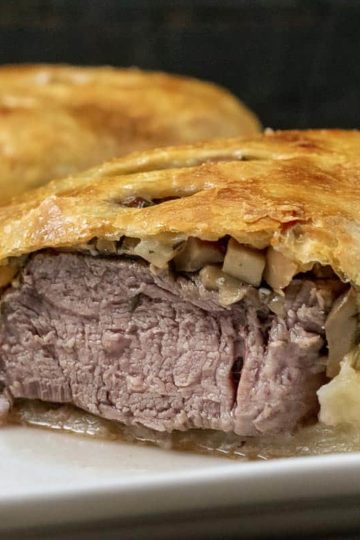 a front view of beef wellington that is cut open to see the filling