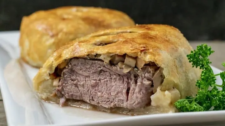 a front view of beef wellington that is cut open to see the filling