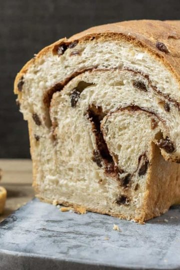Homemade Cinnamon Swirl Raisin Bread on a cutting board and 3 slices laying down