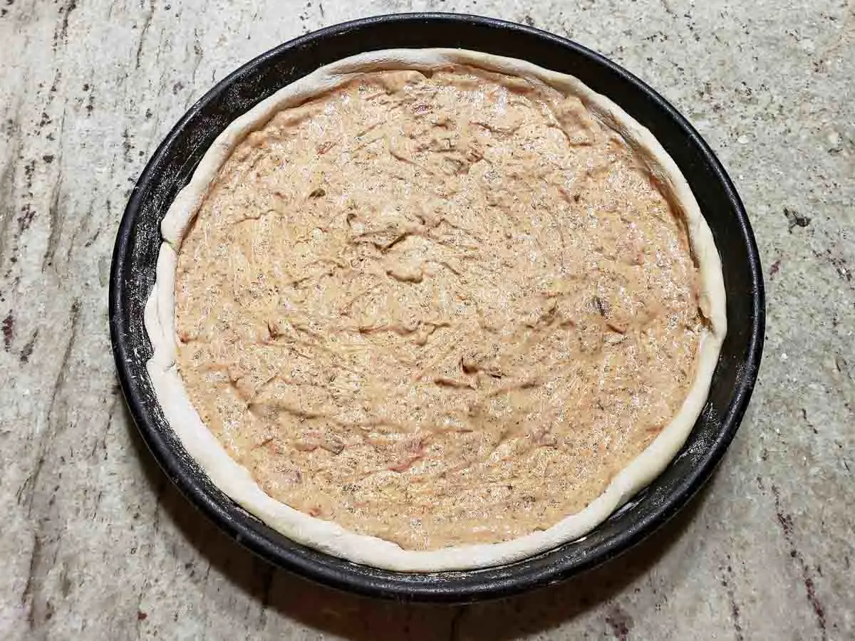 fajita sauce spread on top of dough in pizza pan.
