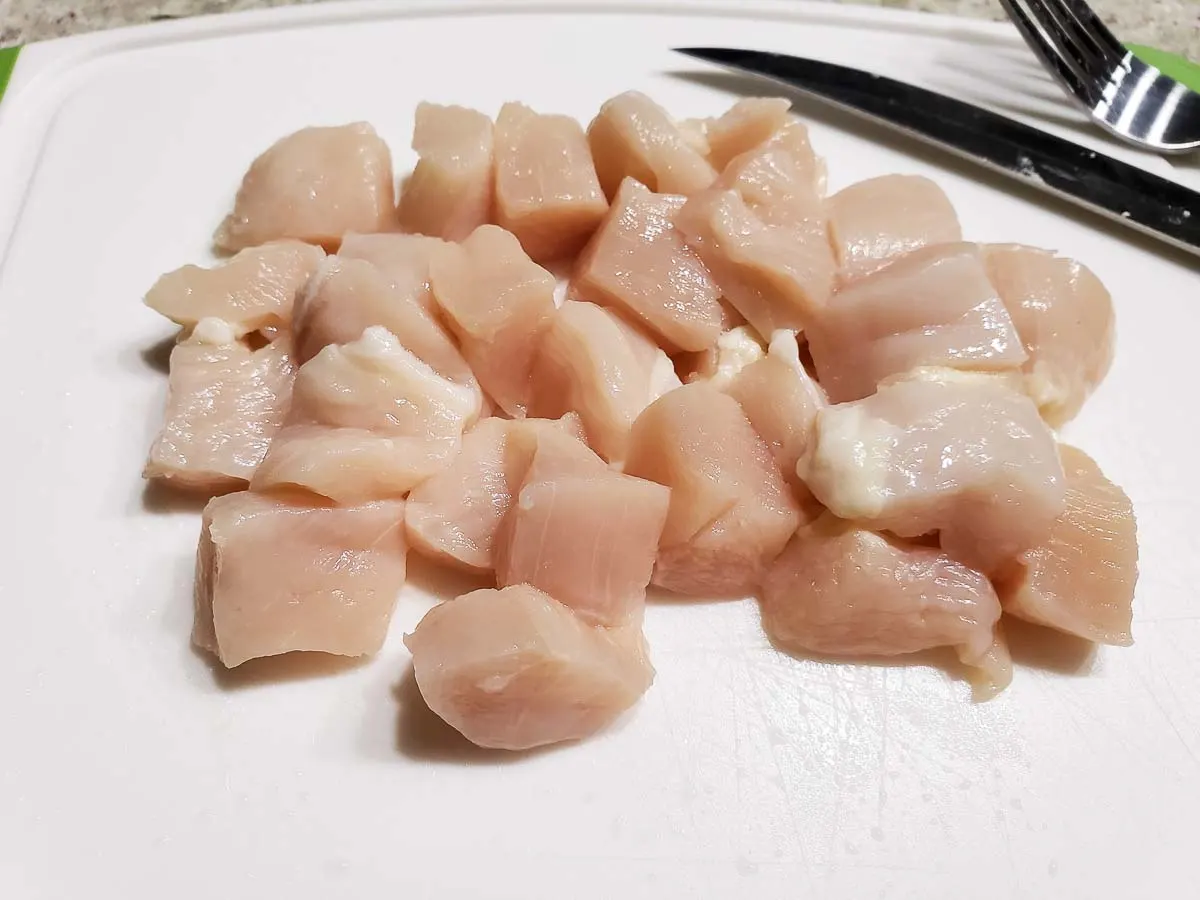 diced chicken on a white cutting board.