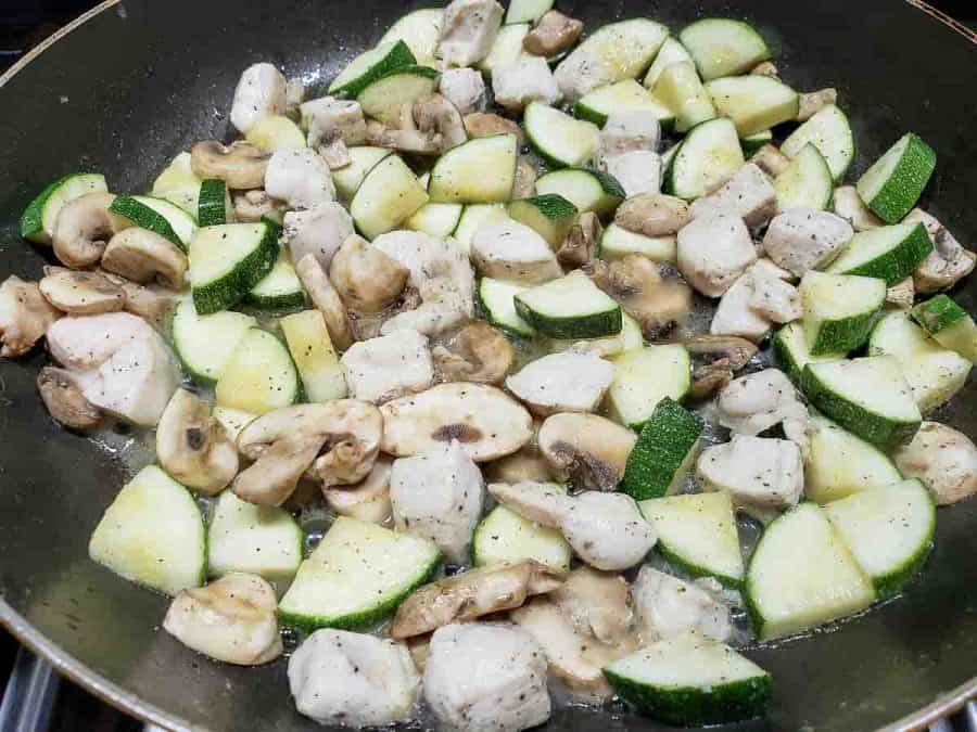  cuisson du poulet, des courgettes et des champignons dans une poêle à frire
