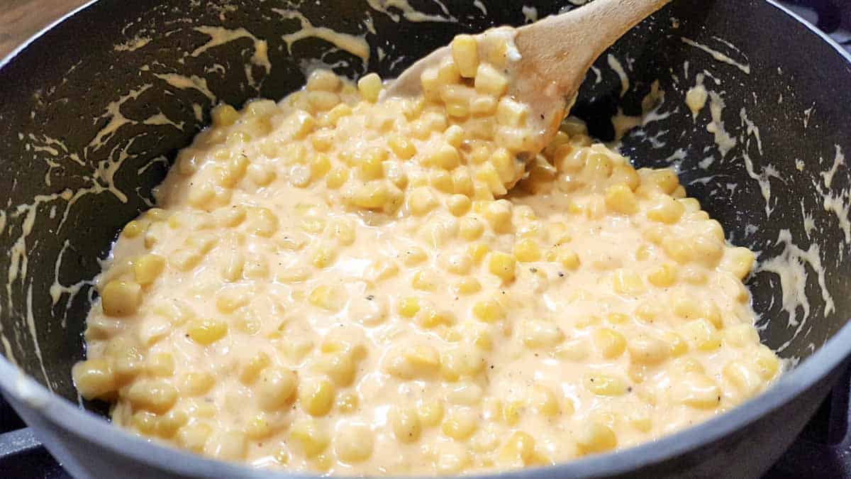 Corn with cream cheese cooking in a pan.