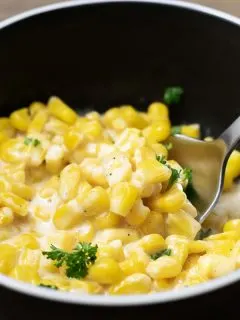 One Pot Cheesy Creamed Corn in a bowl with spoon lifting some corn