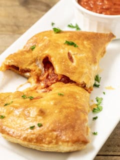 Puff Pastry Pizza Calzone on a tray with a side of pizza sauce.
