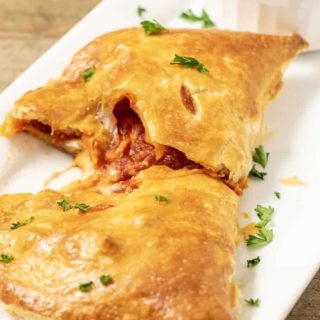 Puff Pastry Pizza Calzone on a tray with a side of pizza sauce.