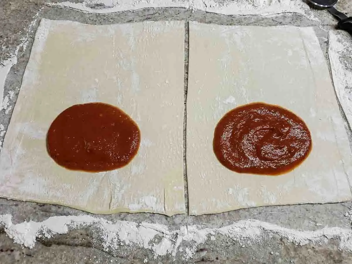 a circle of pizza sauce added to each half of pastry.