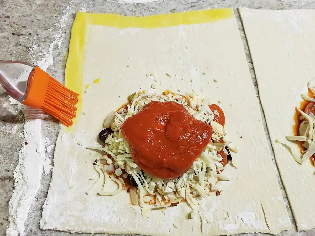 a brush adding beaten egg to the edge of the pastry.