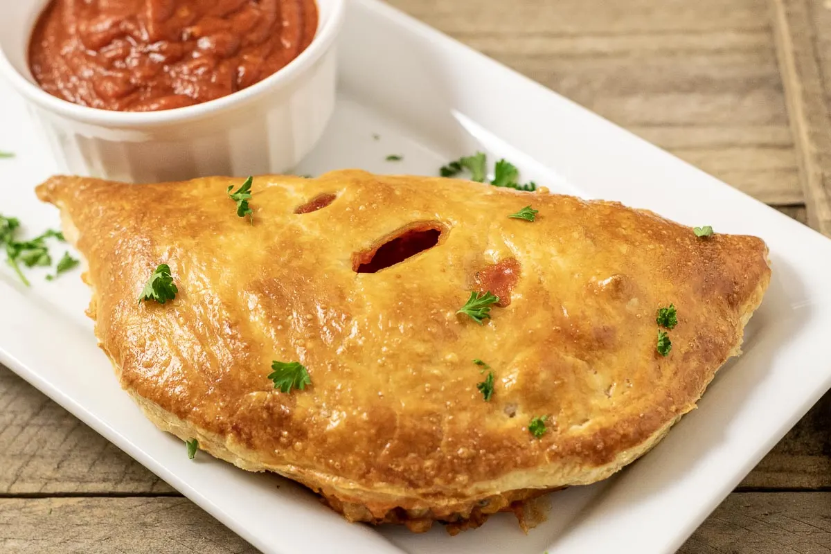 one Pizza Puff Pastry on a platter with a side of pizza sauce.