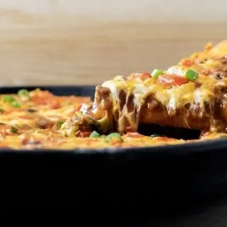 front view of Mexican pizza with a slice being lifted up