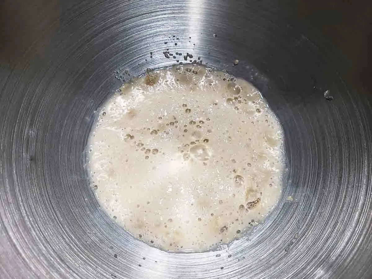 yeast, water, and sugar activating in a bowl.