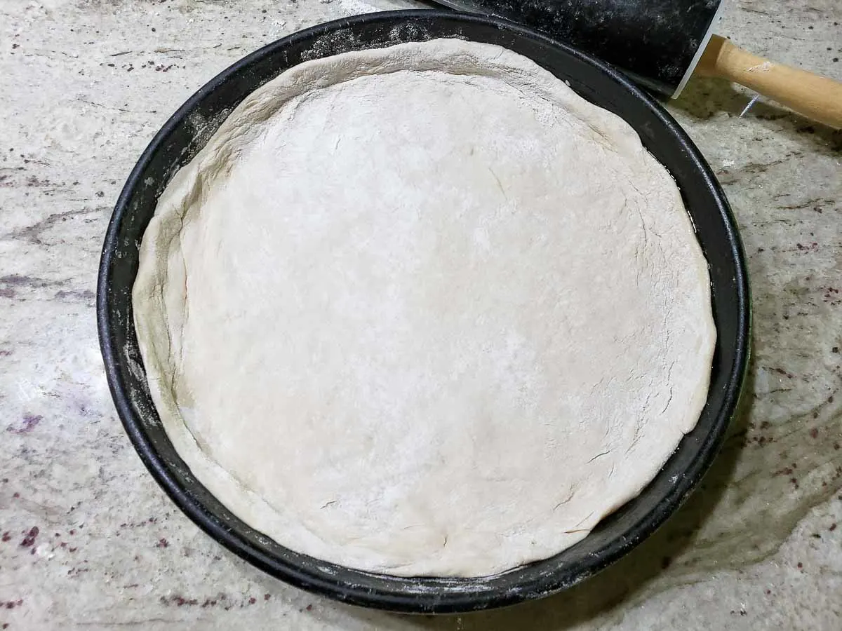 pizza dough pressed into a pizza pan.