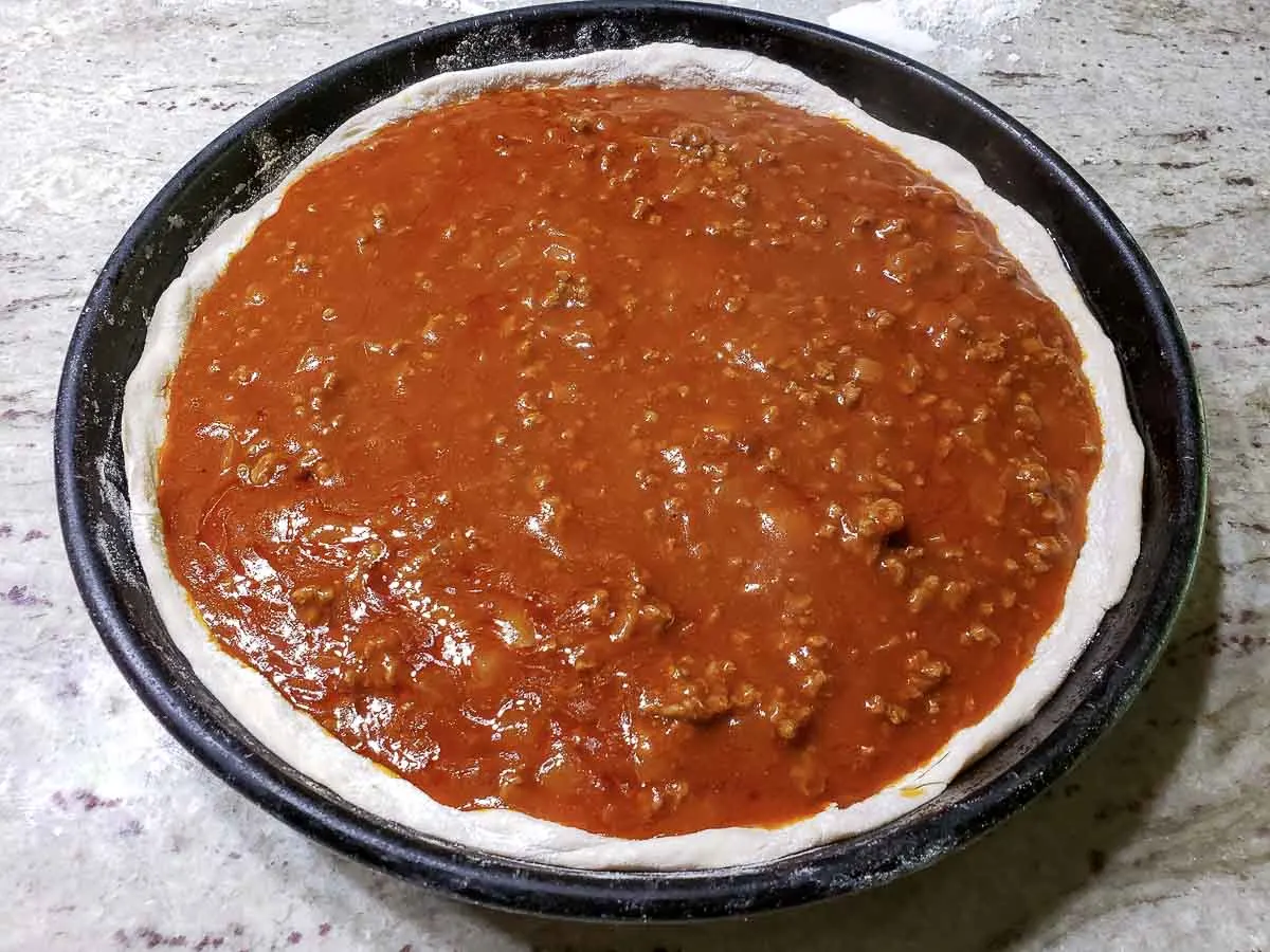 enchilada and ground beef sauce spread over pizza dough.
