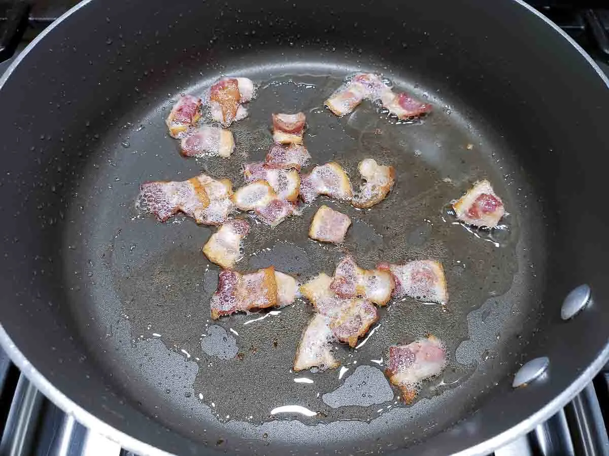 bacon pieces cooking in a pan.