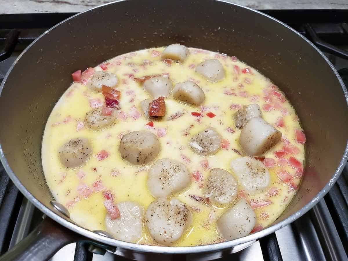cheesy garlic bacon scallops cooking in a pan.