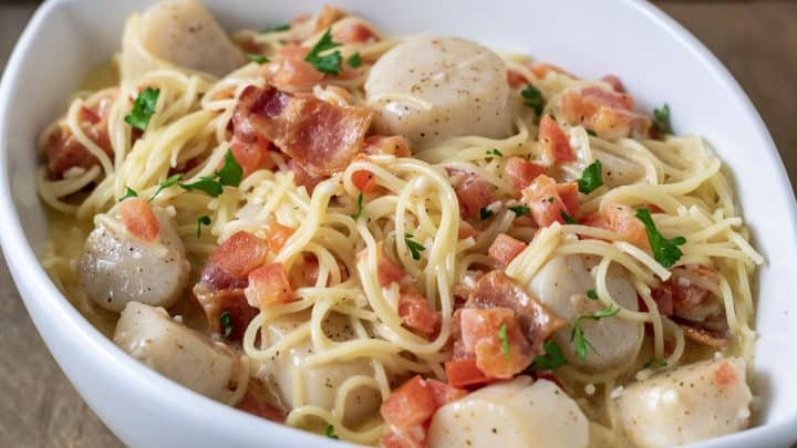 a close up side view of Cheesy Garlic Bacon Scallops and Linguine in a white bowl