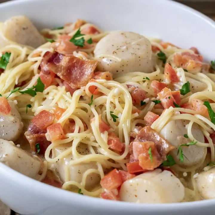 a close up side view of Cheesy Garlic Bacon Scallops and Linguine in a white bowl