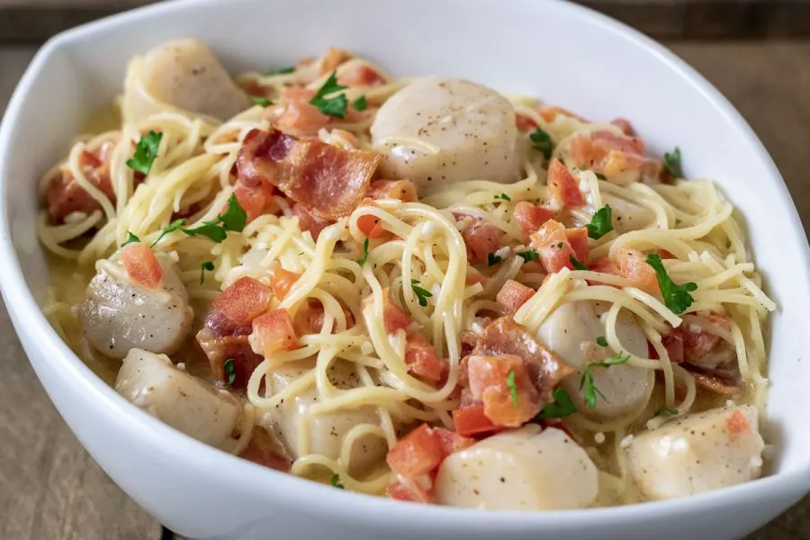 a close up side view of Cheesy Garlic Bacon Scallops and Linguine in a white bowl